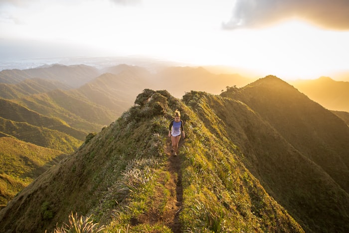 Hiker walking a golden mountain ridge at sunset